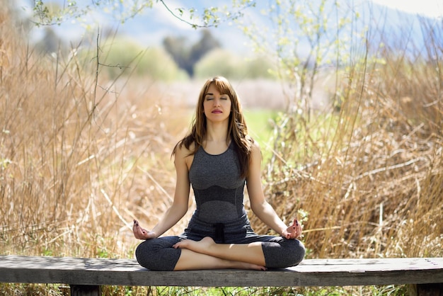 Full length of woman doing yoga on bench over field