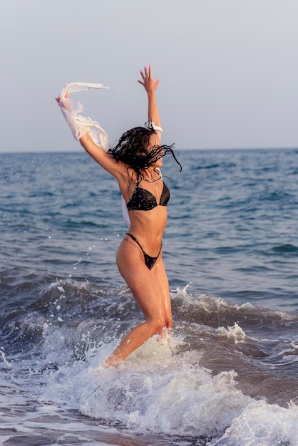 Photo full length of woman with arms raised jumping in sea