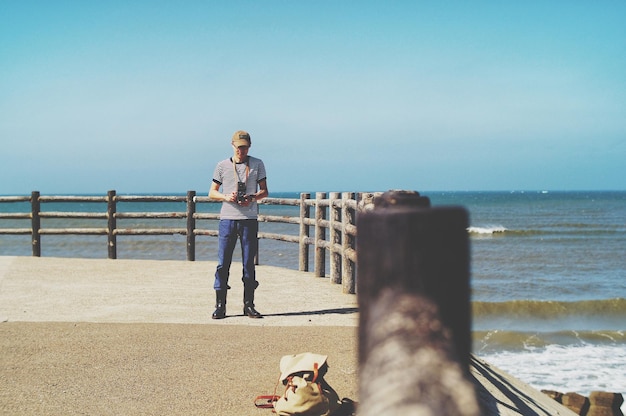 Photo full length of young woman standing against sea