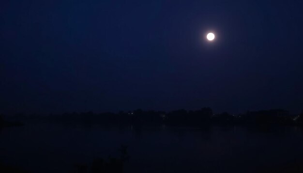 a full moon is shining over a lake in the night