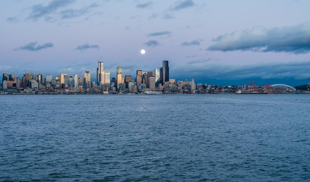 Photo a full moon shines above the seattle skyline