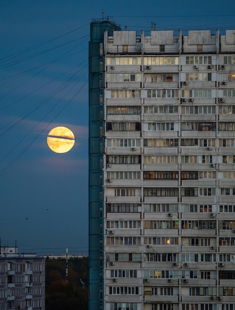 A full moon in the sky and the windows of a multistorey residential building in a residential area