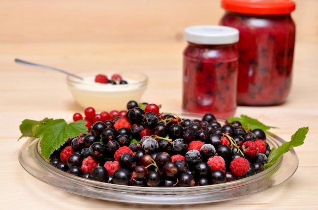 Full plate of berries and jars of jam in the background