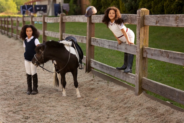 Full shot children learning to ride horses