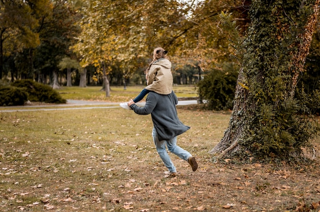 Full shot father carrying girl on shoulders