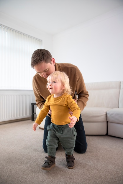 Full shot father helping kid walk