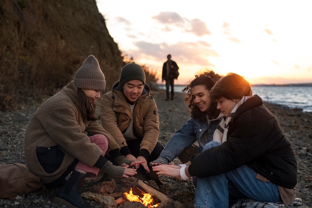 Full shot friends sitting by the fire