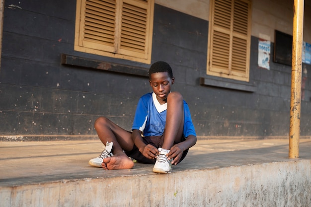 Full shot kid putting shoes on