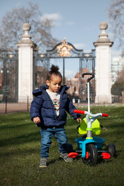 Full shot kid with tricycle in park