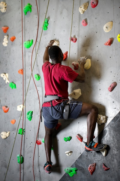 Full shot man climbing wall