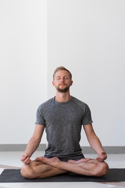 Full shot man doing sukhasana pose indoor