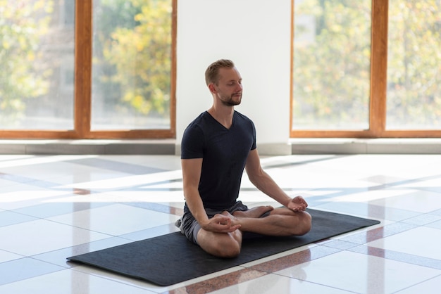 Full shot man doing yoga on mat