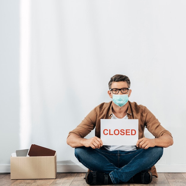 Full shot man holding closed sign