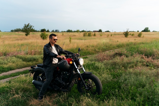 Full shot man with motorbike outdoors