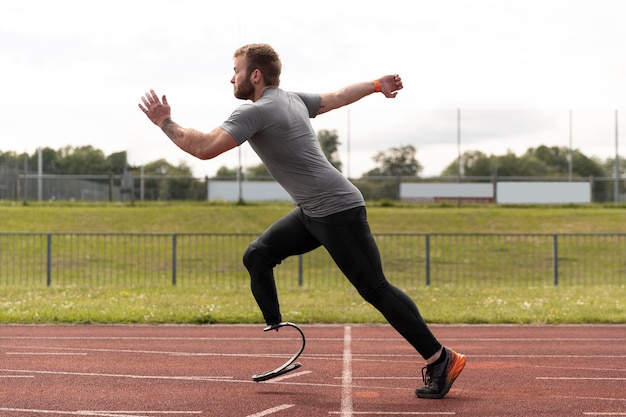 Full shot man with prosthesis running on track