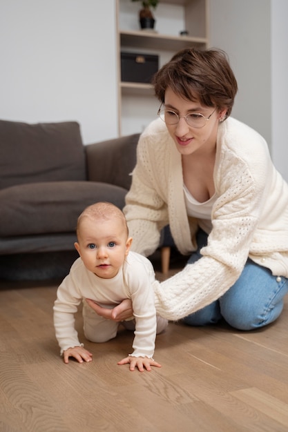 Full shot mother helping baby crawl