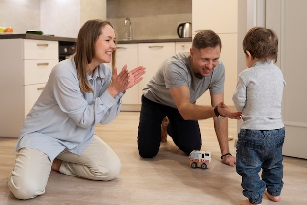 Full shot parents watching kid's first step