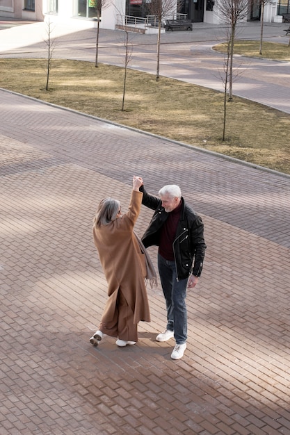 Full shot senior couple dancing outdoors