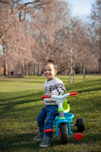 Full shot smiley girl sitting on tricycle