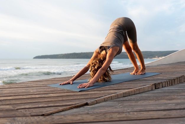 Full shot woman doing yoga near sea