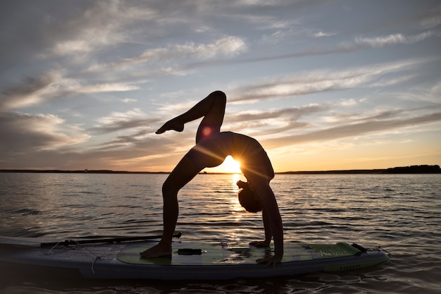 Full shot woman doing yoga on paddleboard