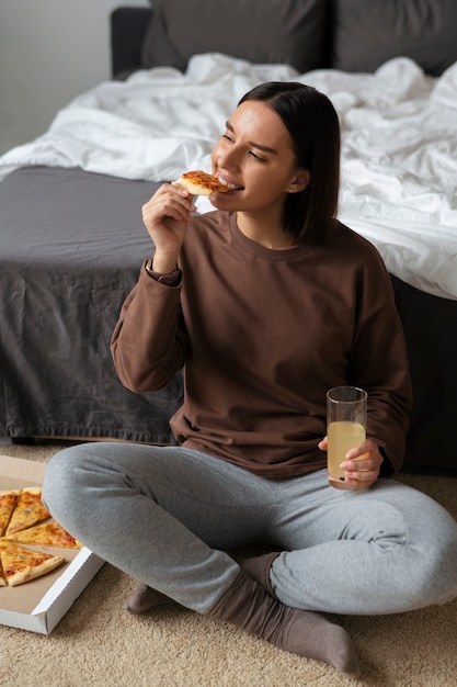 Full shot woman eating delicious pizza