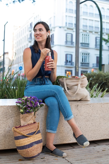 Full shot woman holding juice bottle