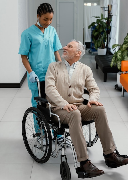 Full shot woman and patient in wheelchair