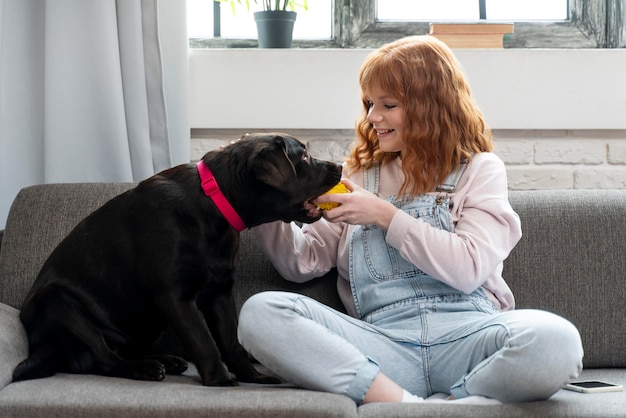 Full shot woman playing with dog on couch