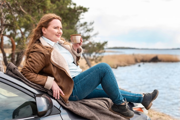 Full shot woman sitting on car