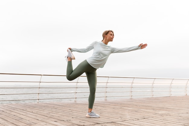 Full shot woman stretching her leg