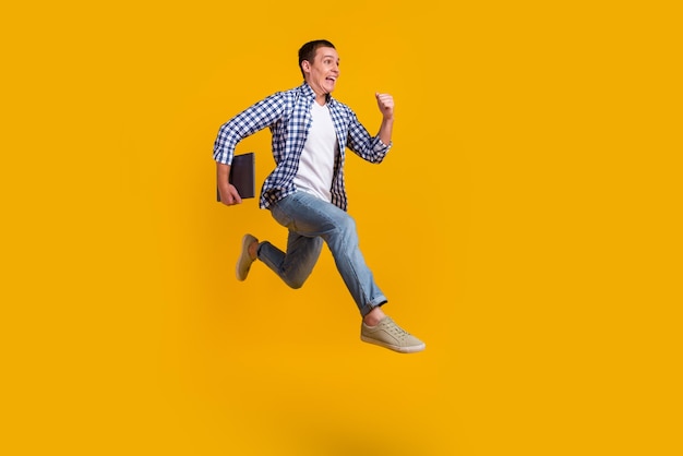 Full size photo of man jump runner sales discounts wear modern trendy outfit isolated over yellow color background