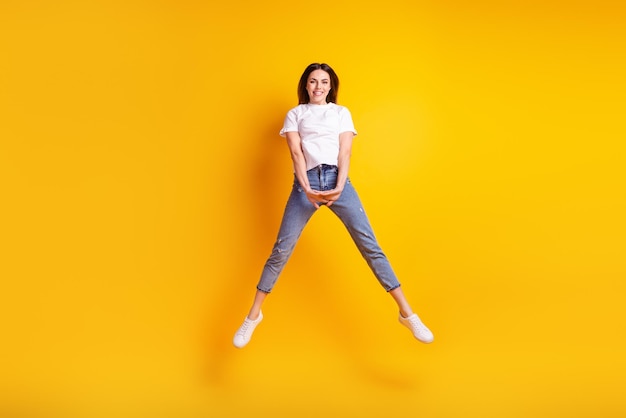 Full size photo of young pretty girl good mood jump up energetic isolated over yellow color background