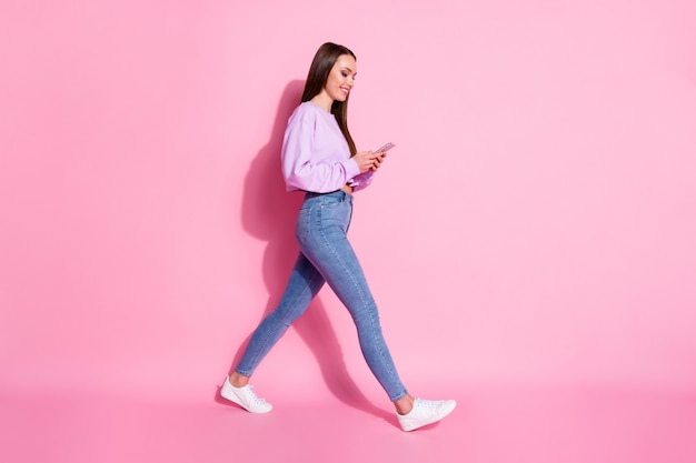 Full size profile side photo of pretty girl blogger go walk use smartphone follow social network news wear lilac violet jumper isolated over pastel color background