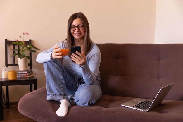 Full view of beautiful woman looking at phone and relaxing at home