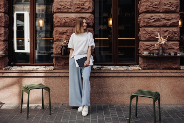 Full view of young woman staying on the street look away