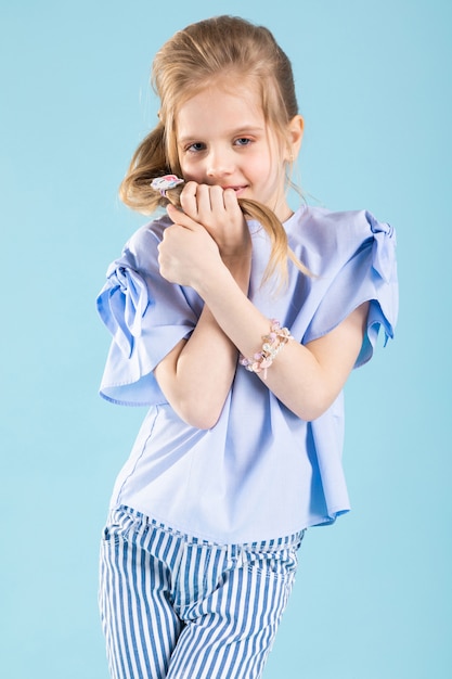 Fulllength portrait of a beautiful girl in blue clothes on a blue wall.