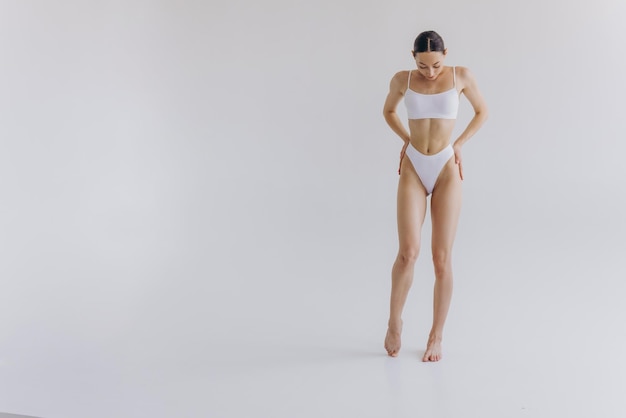 Photo fulllength portrait of beautiful woman with slim body in underwear posing in the white studio background with copy space mockup