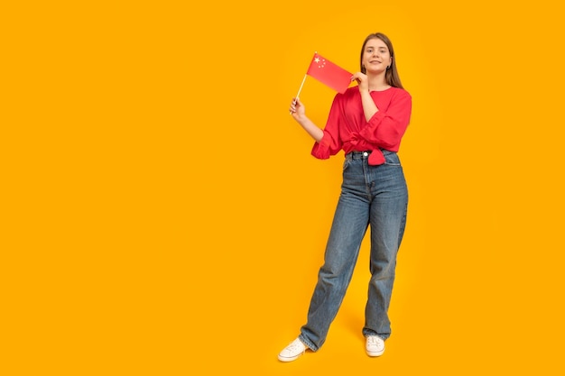 Fulllength portrait of girl holds the flag of China Portrait of girl with the PRC flag on yellow background Learning Chinese