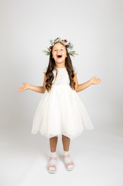 Fulllength portrait of laughing joyful woman in elegant white dress and christmas wreath isolated on...