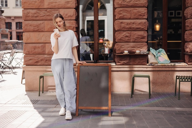 Fulllength view of caucasian woman staying and using her phone