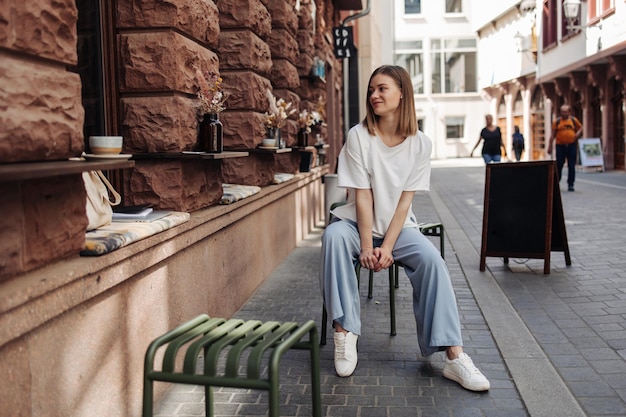 Fulllength view of cute woman sitting at cafe in blue jeans