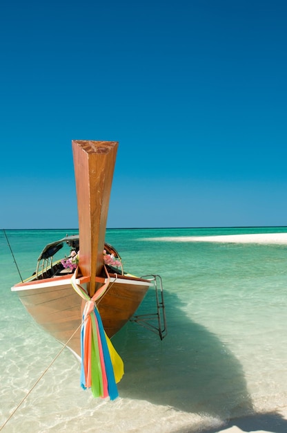 Fully immersed in island life Shot of a boat docked on the shore on a beach in Phuket Thailand