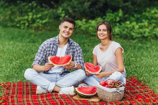 Fun picnic with watermelon. Man and woman eating peace of watermelon in park