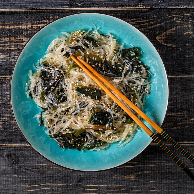 Funchoza salad with wakame on dark background.