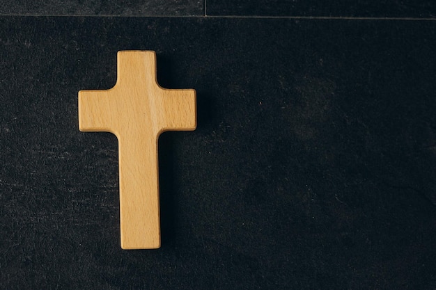 Funeral concept Wooden cross on black background top view copy space