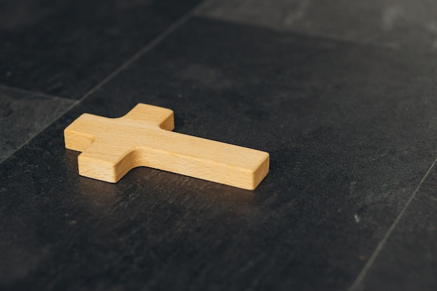 Funeral concept Wooden cross on black background top view copy space