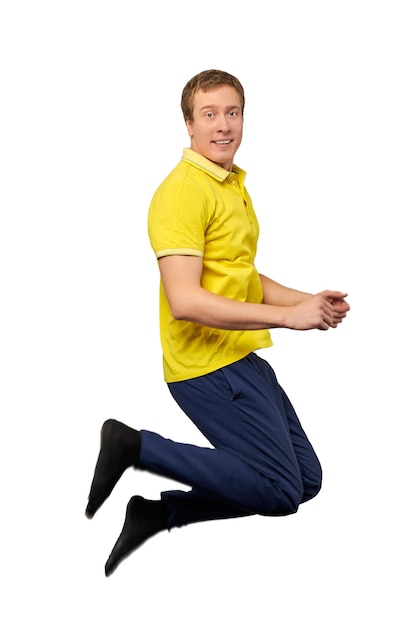 Funny attractive guy in yellow Tshirt and blue pants jumping isolated on white background