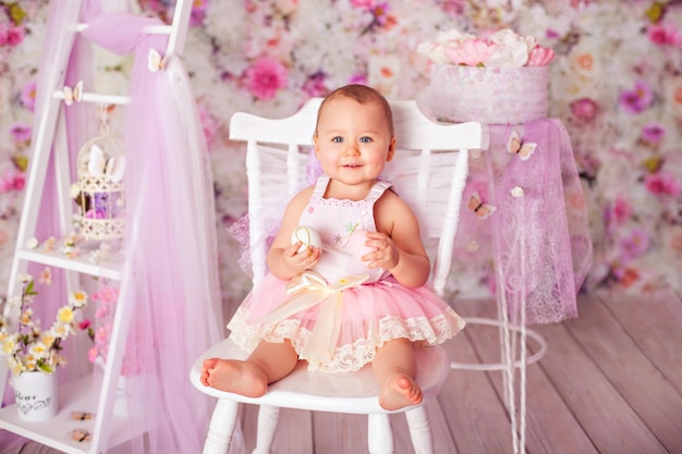 Funny baby girl toddler posing in tutu skirt on flower decoration in studio