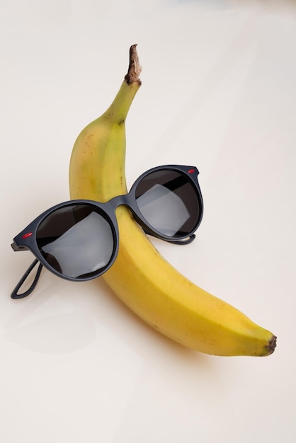 Photo a funny banana with black sunglasses on a white background